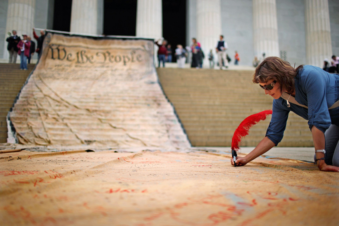 A woman writes on a giant banner printed with the Constitution during a demonstration against the Supreme Court's Citizens United ruling at the Lincoln Memorial on Oct. 20, 2010, in Washington, DC.