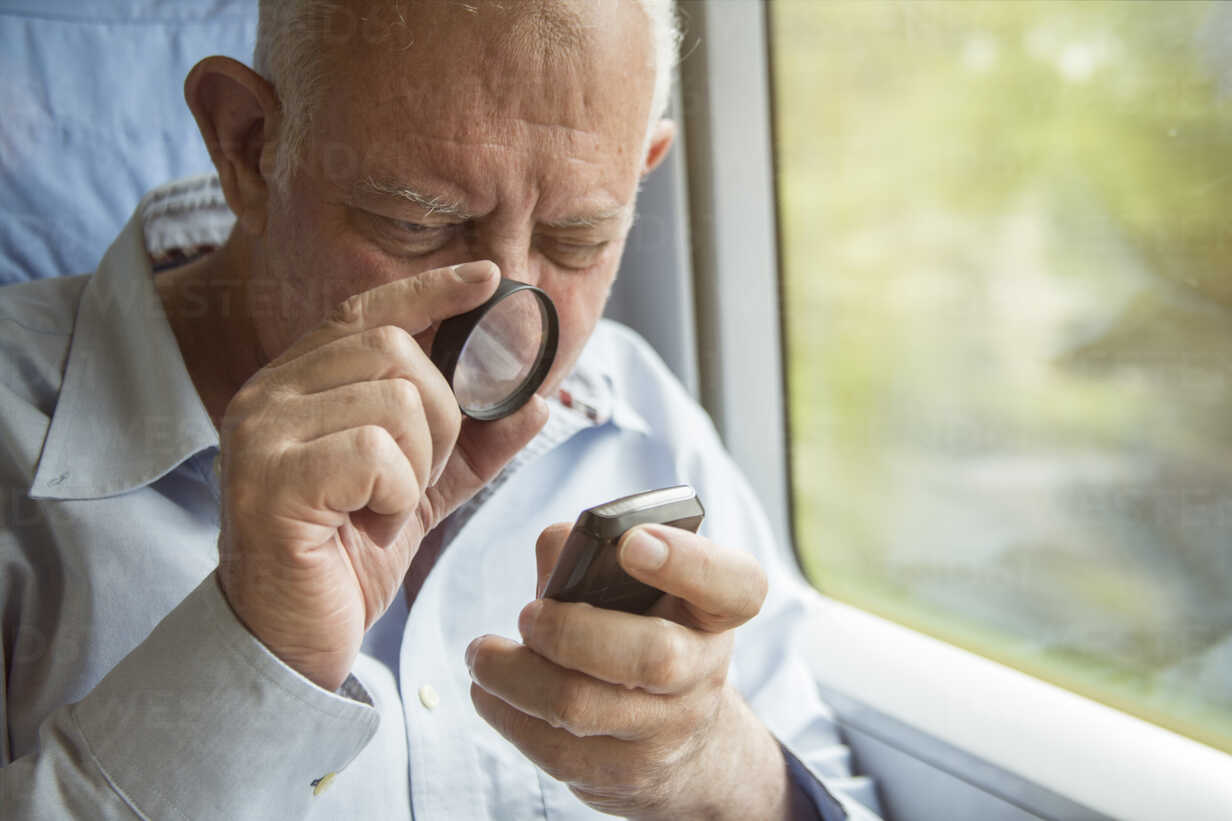 senior-man-reading-text-on-a-cell-phone-with-a-magnifying-glass-TAMF000123.jpg